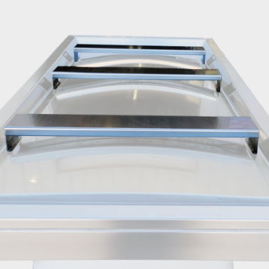 A set of three American Mortuary stainless steel body bridges positioned on a hydraulic embalming table, highlighting the high-clearance drainage design and adjustable positioning for professional remains preparation.