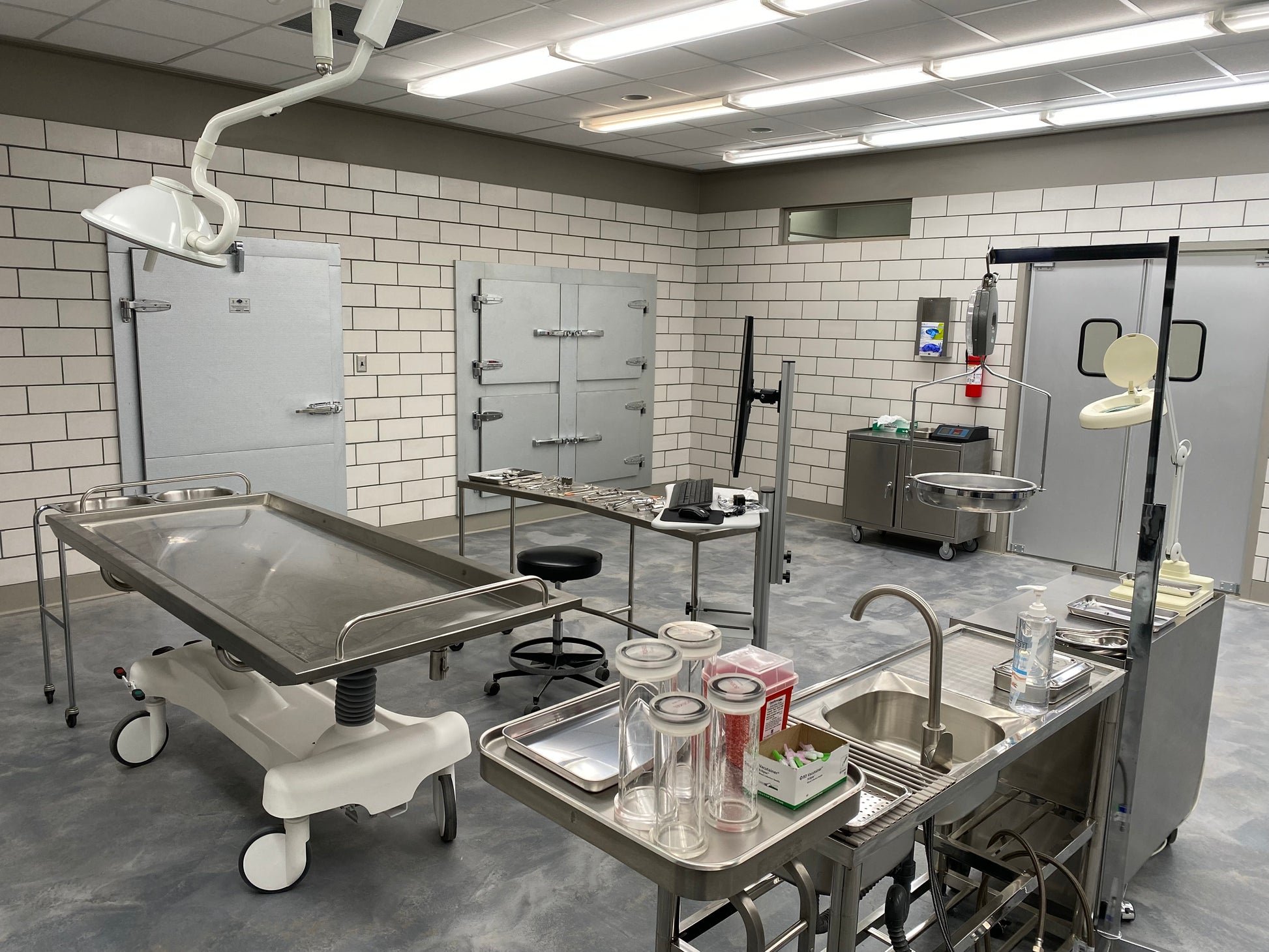 Hydraulic embalming table foot-pedal height adjustment and reinforced enclosed stainless steel pedestal base