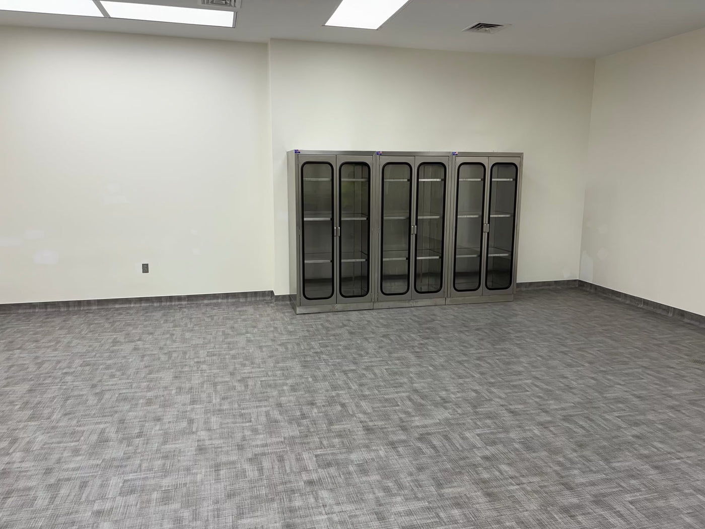 Four USPE stainless steel glass-front storage cabinets installed in a laboratory room; actual project photograph